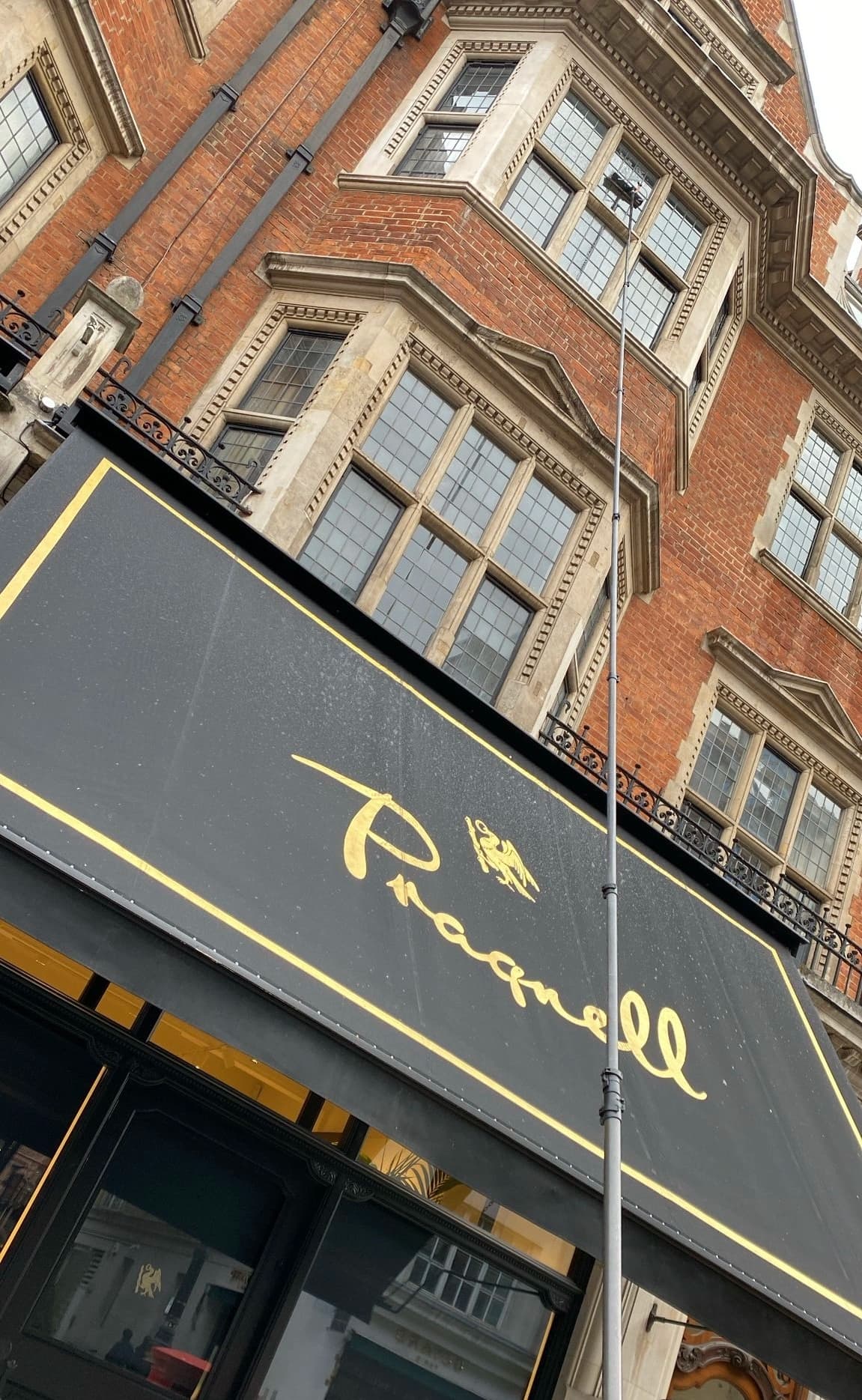 Reaching sash windows above a shop awning on a red-brick period building.