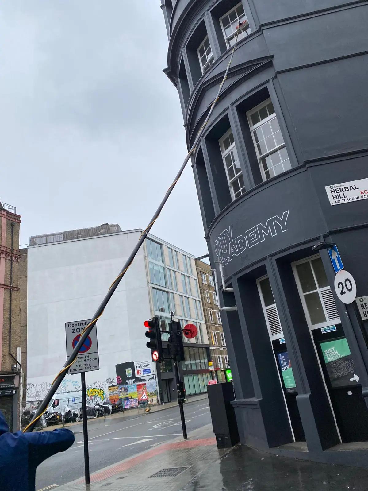 Reaching the upper windows of a curved commercial building with a water-fed pole.